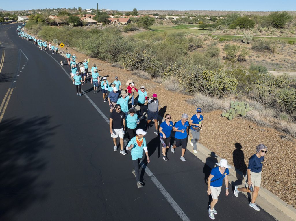 Walkers stream down the road in SaddleBrooke, many of them wearing bright turquoise shirts.